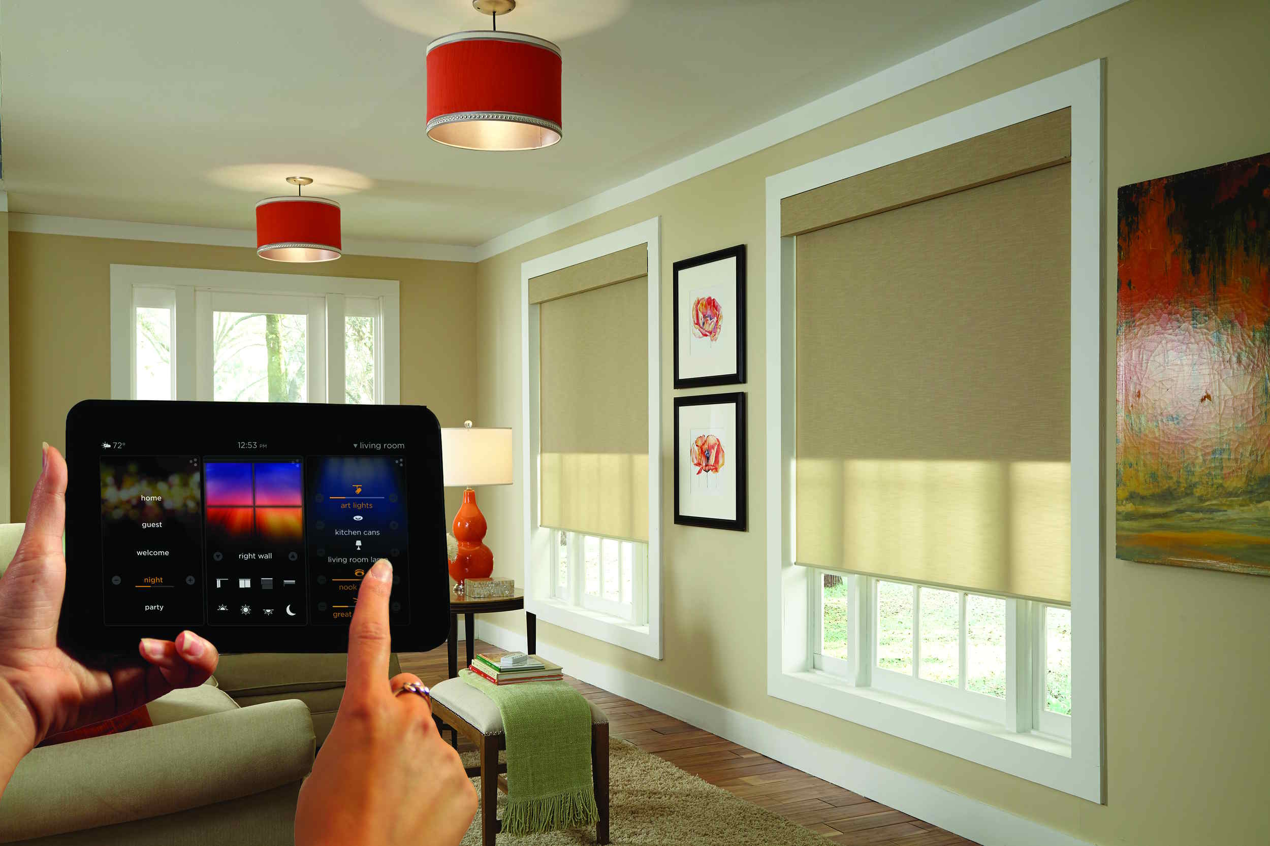 Person controlling motorized window shades with a smart home tablet in a living room.