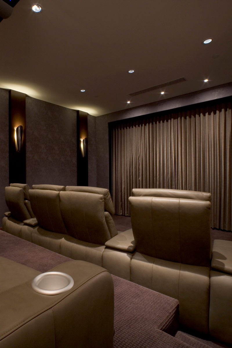 Luxury home theater room with leather recliner seats and curtained screen.