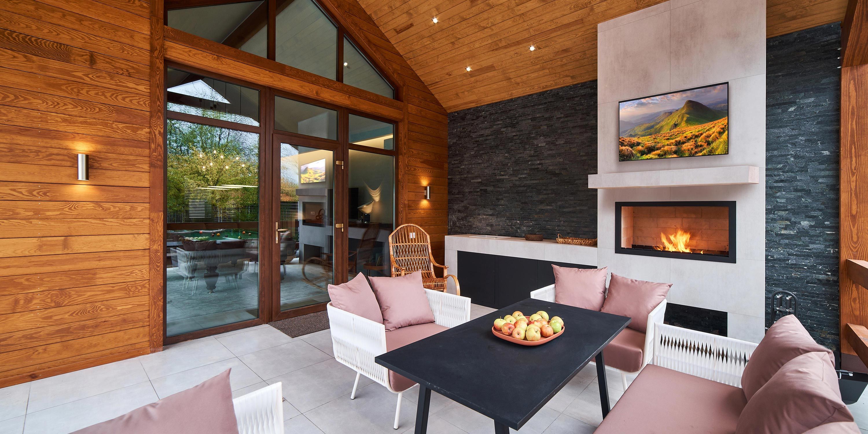 Cozy covered porch with a fireplace, modern seating, and wooden accents.