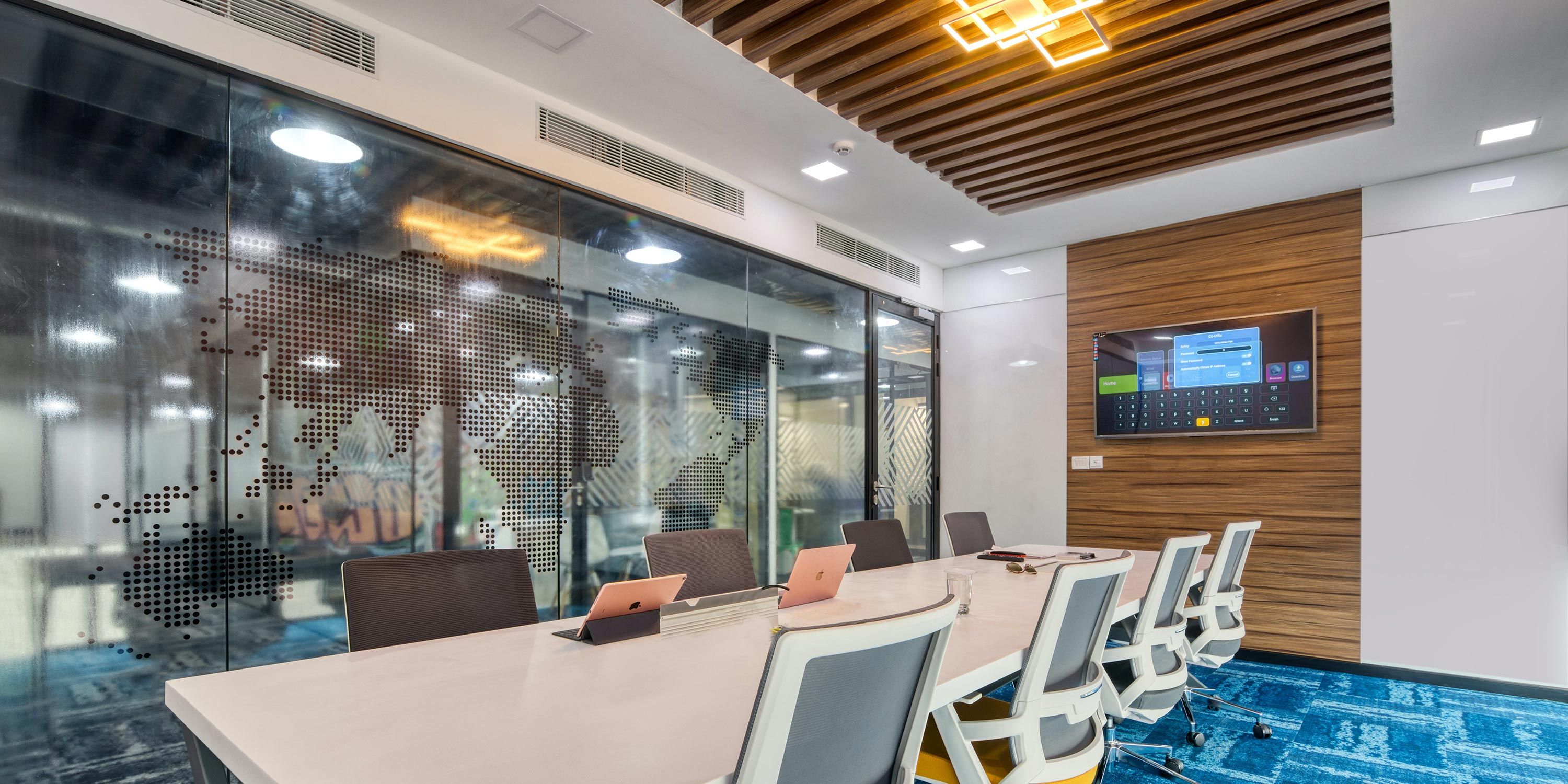 Contemporary conference room with a long table, ergonomic chairs, and a large screen.