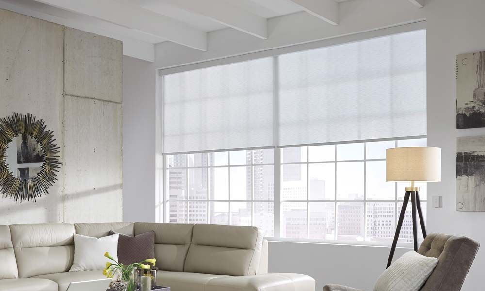 Modern living room with Lutron solar shades, a large sectional sofa, and a view of the city skyline.