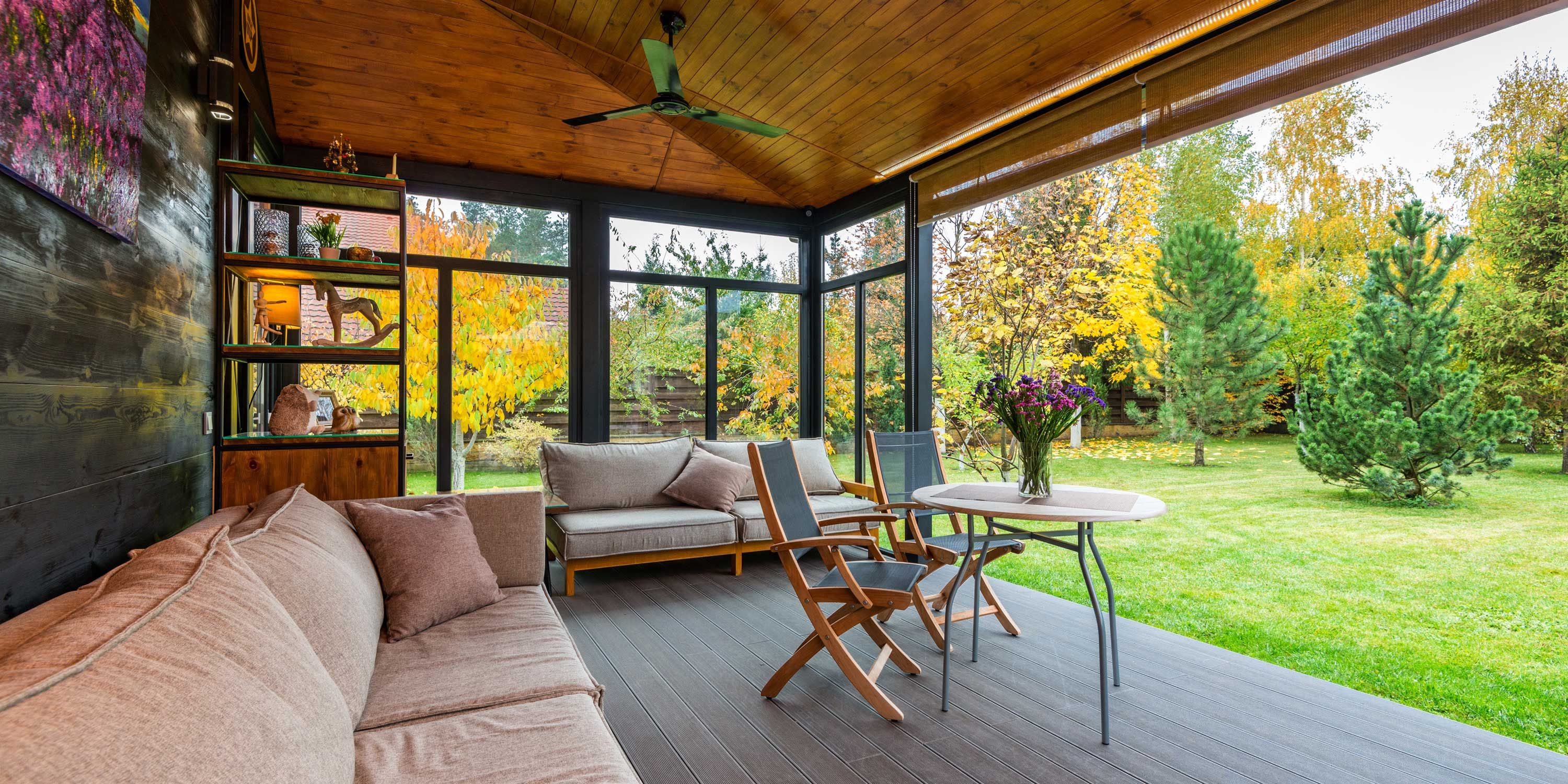 Enclosed porch with comfortable seating, surrounded by a lush garden.