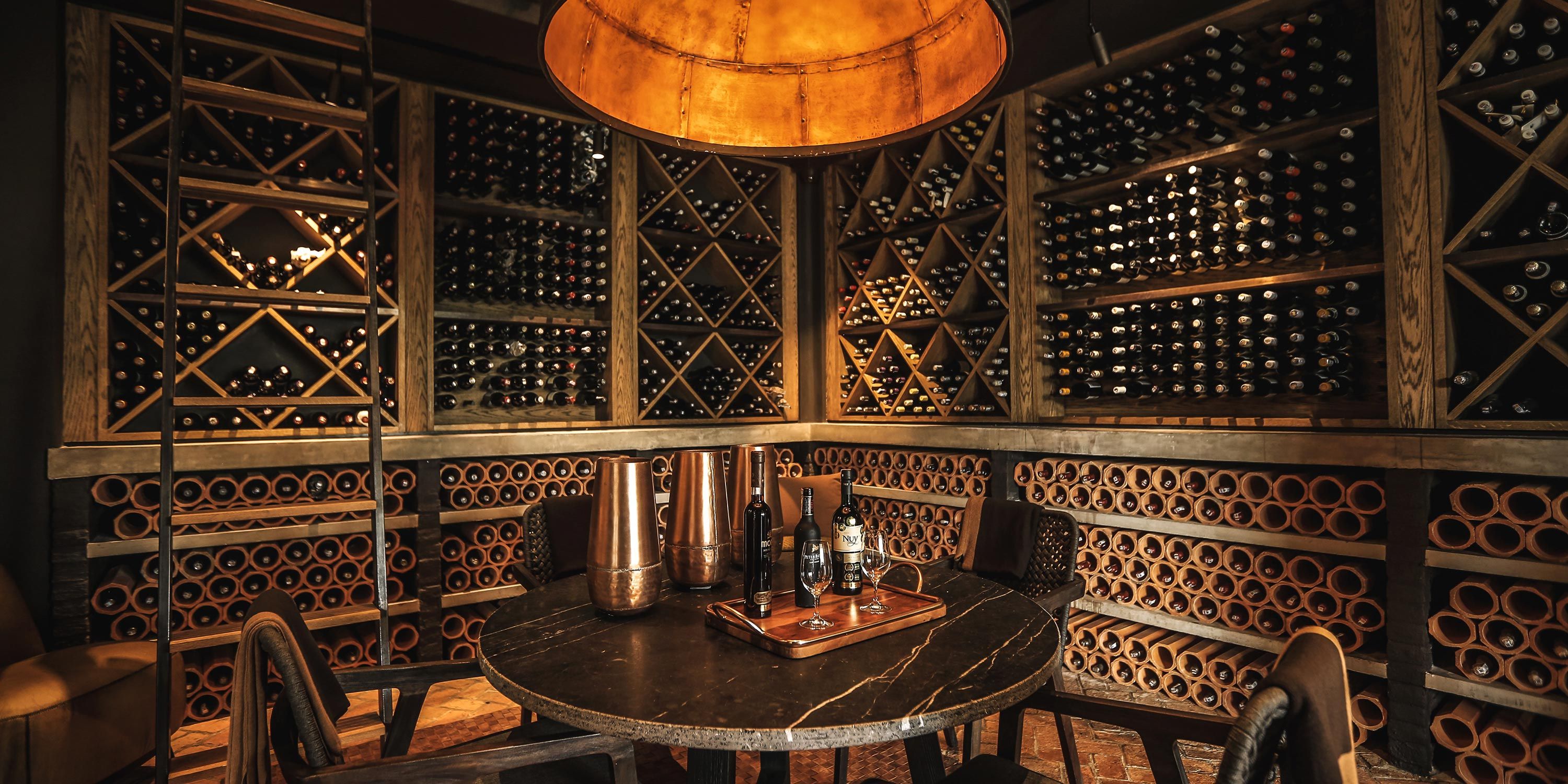 Luxurious wine cellar with extensive bottle storage, a central table, and warm ambient lighting.