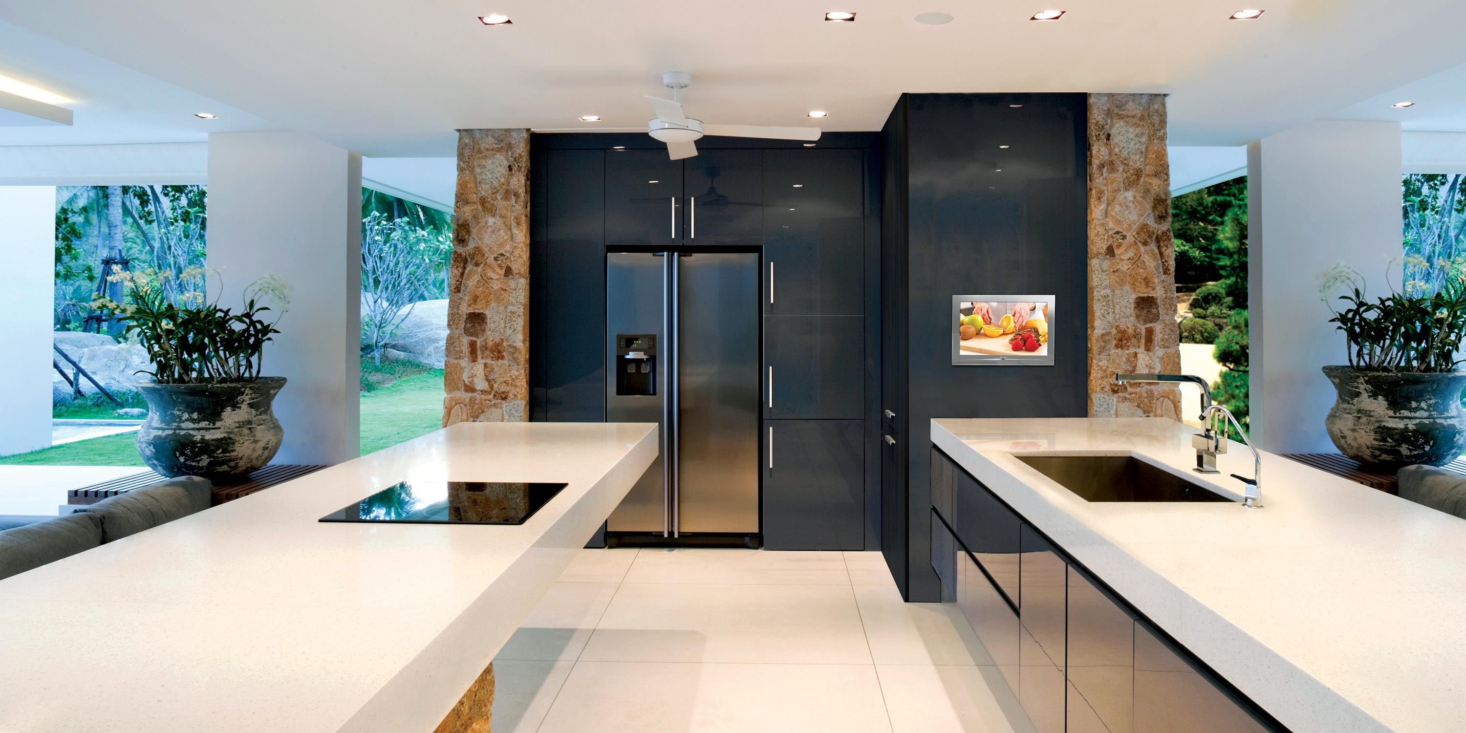 Contemporary kitchen with sleek countertops, stainless steel appliances and a Seura Waterproof TV, and large windows opening to a garden.